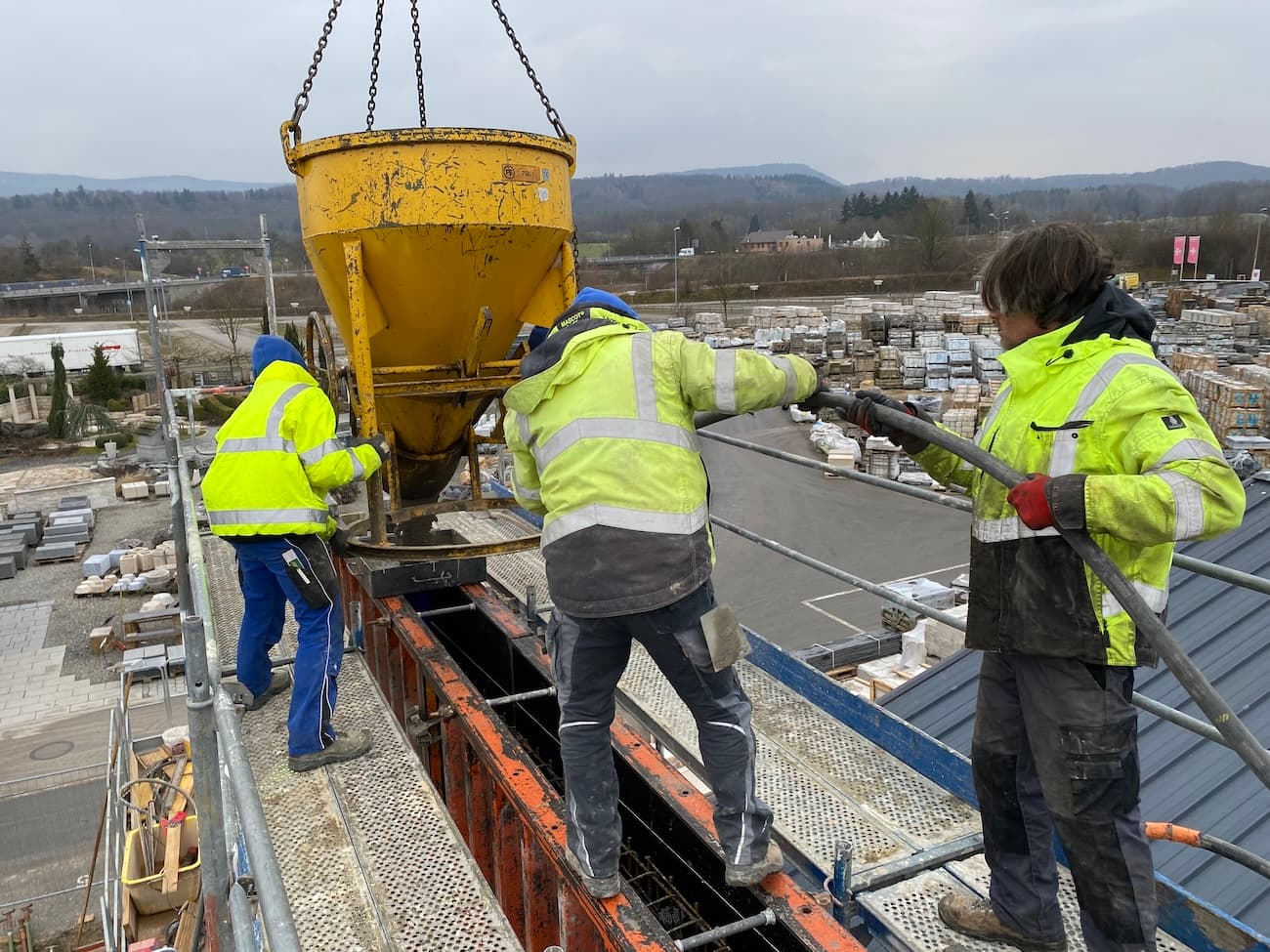 Bauarbeiter beim Betonieren mit Kübel auf einer Rohbaustelle